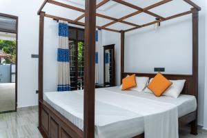 a bedroom with a canopy bed with orange pillows at Blue Heaven Villa Ahangama in Ahangama +44 photos
