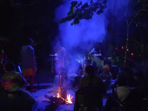 a group of people sitting around a fire at night at Bridge Point Home Stay in Kushālnagar