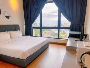 a bedroom with a bed and a desk and windows at The Apple Suites Melaka in Melaka