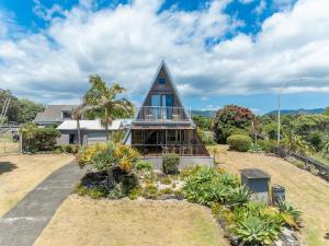 a house with a gambrel roof with a balcony at Ahiparadise - Ahipara Holiday Home in Ahipara