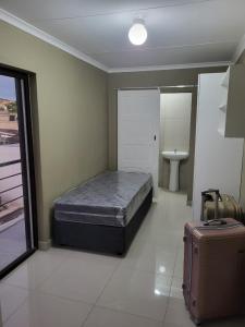 a bedroom with a bed and a suitcase in it at Park Q Residence in Pimville