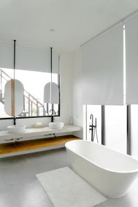 ein weißes Badezimmer mit zwei Waschbecken und einer Badewanne in der Unterkunft Casa Luna Villa in Kerobokan