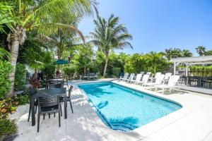 a swimming pool with chairs and a table next to a pool at Blissful Bay at Bayside Bungalow in Anna Maria