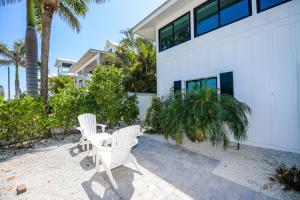 two white chairs and a table in front of a building at Blissful Bay at Bayside Bungalow in Anna Maria