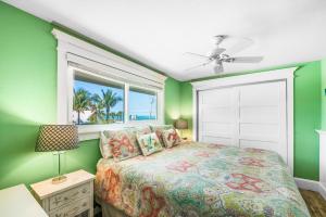 a bedroom with green walls and a bed with a window at Blissful Bay at Bayside Bungalow in Anna Maria +30 photos
