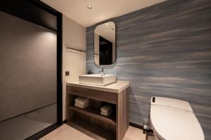 a bathroom with a sink and a toilet and a mirror at Grand Mercure Okinawa Cape Zanpa Resort in Yomitan