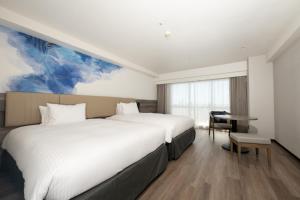 a hotel room with two beds and a desk at Grand Mercure Okinawa Cape Zanpa Resort in Yomitan