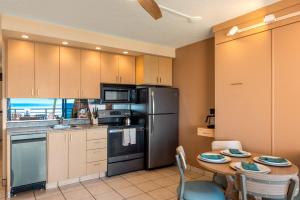 a kitchen with a table and a stainless steel refrigerator at Kuleana Club #510 - Ocean View -1 bedroom & 1 bathroom - 2nd Floor in Kahana