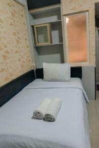 uma cama com dois pares de chinelos sentados nela em Comfort and Cozy Studio Student Castle Yogyakarta Apartment By Travelio em Seturan