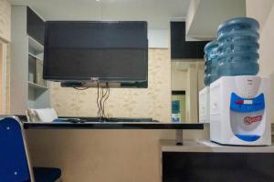 uma mesa com um monitor de computador e uma garrafa de água em Comfort and Cozy Studio Student Castle Yogyakarta Apartment By Travelio em Seturan