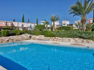a large blue swimming pool in front of some buildings at Villa Valendra in Peyia