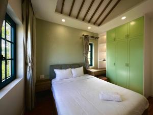a bedroom with a large white bed and green cabinets at NOVAWORLD PHAN THIET SUNRISE VIILLA 4pn in Bình Tú