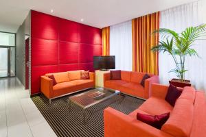 a living room with two orange couches and a tv at Mamaison Residence Diana in Warsaw