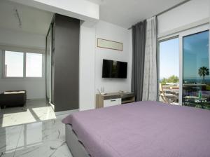 a bedroom with a purple bed and a balcony at Villa Valendra in Peyia