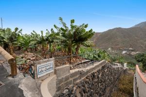 a sign on a wall next to a bunch of banana trees at Casa Rural La Cuadra in Hermigua