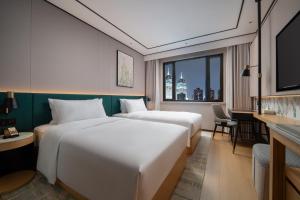 Un ou plusieurs lits dans un hébergement de l'établissement Hilton Garden Inn Shanghai Caoyang