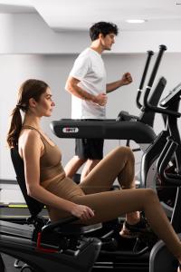 a man and woman riding on a treadmill in a gym at Athenian Riviera Hotel& Suites in Athens