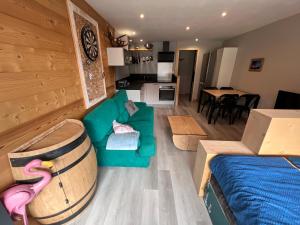 a living room with a green couch and a wine barrel at Le studio de mimi in Le Grand-Bornand