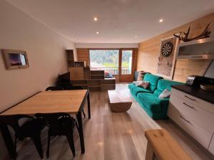 a living room with a green couch and a table at Le studio de mimi in Le Grand-Bornand