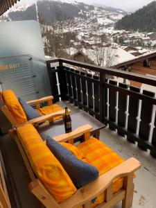 a balcony with two chairs and a bottle of beer at Le studio de mimi in Le Grand-Bornand