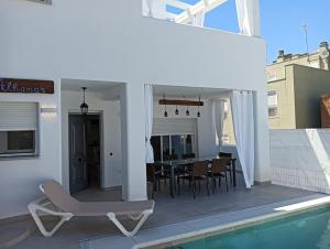 un patio con tavolo e sedie accanto alla piscina di Nueva Casa Alhamar a Punta Umbría