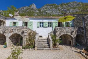 ein Haus mit einem Steingebäude mit einem Sonnenschirm in der Unterkunft Einzigartiges mediterranes Steinhaus mit Meerblick, Chillout-Bereich, Bike, BBQ, WiFi in Grižane