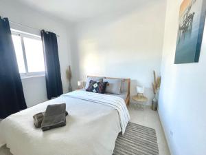 a bedroom with a large white bed with a window at Casa da praia in Aljezur