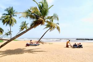 a group of people sitting on a beach with palm trees at Fanisha Family Villa and Restaurant in Negombo