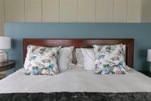 a bed with white pillows and a wooden headboard at Breakwaters on Pezula in Knysna