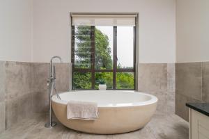 a bath tub in a bathroom with a window at Breakwaters on Pezula in Knysna