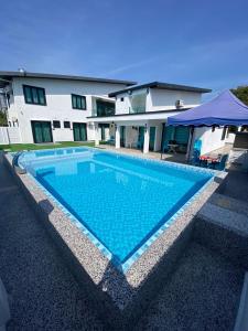 a large blue swimming pool in front of a house at MERCU STAYCATION HOMESTAy in Lengging