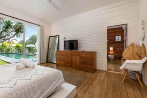 una camera da letto con un letto, una tv e una finestra di Villa Ikebana - Trendy 5BR Spacious Villa with Rice Field Views, Large Pool, and 5 Minutes to Canggu a Kerobokan