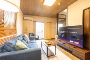 a living room with a blue couch and a large tv at Miro Fusimiinari Tei North in Kyoto