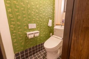 a bathroom with a toilet and a green wallpaper at Miro Fusimiinari Tei North in Kyoto +13 photos