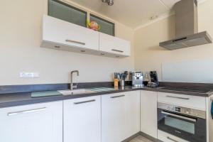 a kitchen with white cabinets and a sink at Appartementencomplex Juliana 148 in De Koog