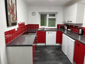 a red and white kitchen with white cabinets and red tiles at The Lodge in Lochgilphead