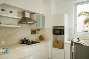 a white kitchen with a stove and a window at La Olalian by The Blue Kite - 2 & 3 BHK Designer Villas Near Anjuna Beach with Private Pool & Sun Deck & Garden in Anjuna