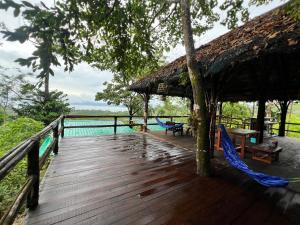 a wooden deck with a hammock and a pool at Tiger home stay Phayam in Ko Phayam