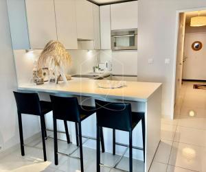 a kitchen with a counter with chairs and a table at LONDON CANNES, vue mer in Cannes