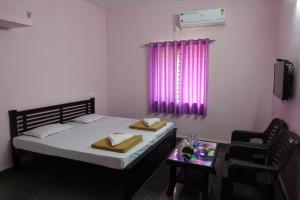 a bedroom with a bed and a table and a window at Veerashaiva Yatri Nivasa in Gokarna