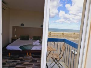 a bedroom with a bed and a view of the beach at Hotel de la Plage - Barcares in Le Barcarès