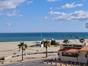 a building on the beach with palm trees and the ocean at Hotel de la Plage - Barcares in Le Barcarès