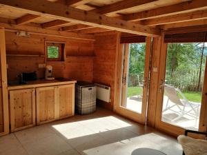 a kitchen in a log cabin with a sliding glass door at Cabanon in Sapois