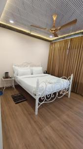 Cette chambre comprend un lit blanc et un ventilateur de plafond. dans l'établissement Hotel Golden Heritage Deluxe, à Jaipur