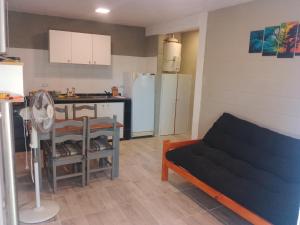 Una cocina y una sala de estar con un sofá. en Cabaña Calamuchita Rumipal, en Villa Rumipal