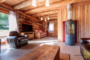 a living room with a fireplace in a log cabin at Chalet de Fougerousse in Chambon-sur-Lac