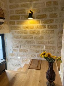 a vase with flowers in a room with a brick wall at CASA ENRICA in Adelfia