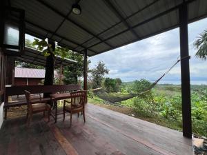 Un porche con una hamaca y una mesa y sillas. en Tiger homestay 2 Phayam, en Ko Phayam