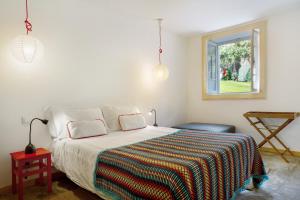 una camera da letto con un letto con una coperta colorata e una finestra di Calheta Beach House T1 a Calheta