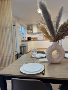 a wooden table with plates and a vase on it at Maison des chênes in Bavilliers +3 photos